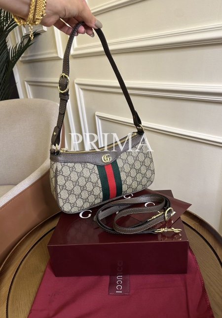 حقيبة كتف صغيرة من مجموعة Gucci Ophidia. تتميز الحقيبة بتصميمها الكلاسيكي المستوحى من أرشيف غوتشي، وهي مصنوعة من قماش GG Supreme الكلاسيكي باللون البيج والأبنوسي ومعها حزام طويل مختومة. فل باكج قاعدة 25 سم