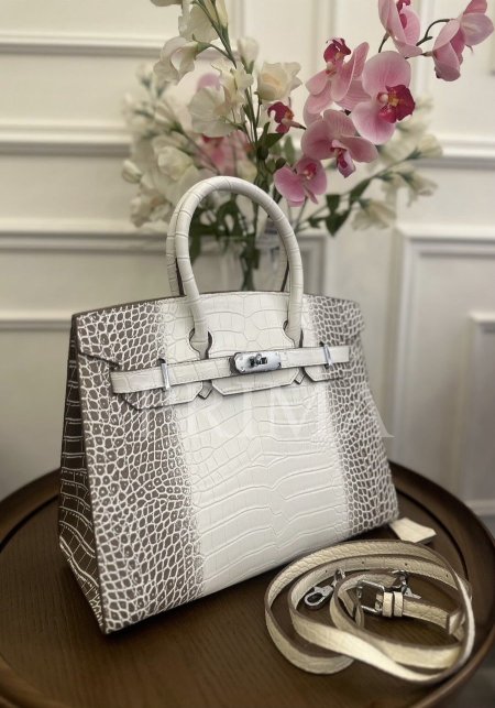 حقيبة فاخرة، من طراز "بيركين" الشهير من هيرميس أو مستوحاة منه،معها حزام طويل للكتف . وتتميز بجلد التمساح  اللامع. جودة عالية جدا وسعر خيالي بالنسبة للجودة غير مختومة . قاعدة 30 سم